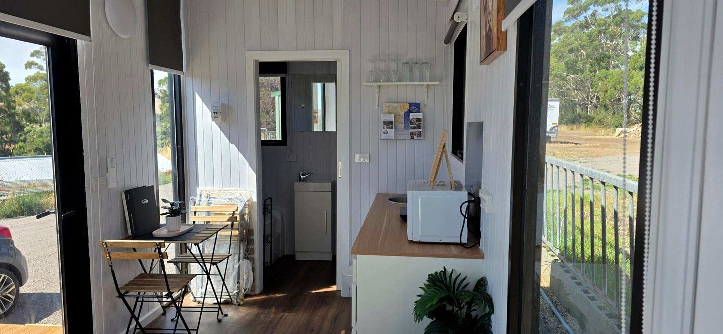 A compact room with a kitchenette, a dining area with a table and chairs, and a view of the outdoors.