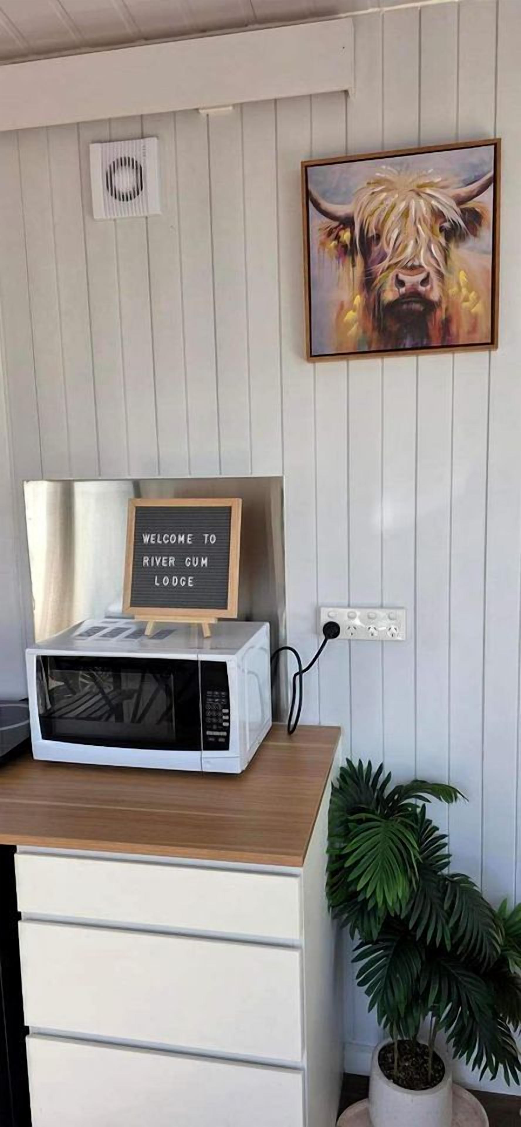 A kitchen counter with a microwave, a welcome sign, and a potted plant.