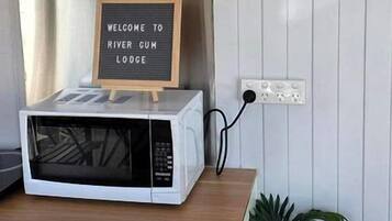 A kitchen counter with a microwave, a welcome sign, and a potted plant.