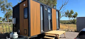 A compact, modern structure with a wooden exterior, a sliding door, and a small outdoor seating area.