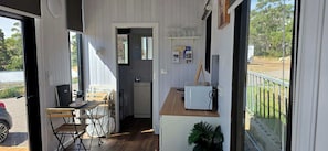 A compact room with a kitchenette, a dining area with a table and chairs, and a view of the outdoors.