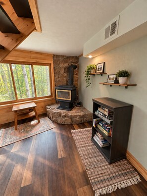A cozy room with a stone fireplace, wooden shelves, a bench, and a large window. - Stunning Luxury Chalet with Attached Garage (Bessemer)