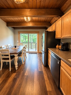 A wooden interior with a dining table, chairs, a refrigerator, and a coffee maker. - Stunning Luxury Chalet with Attached Garage (Bessemer)