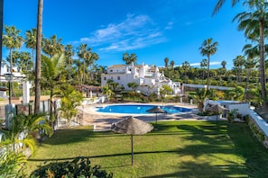 Ein Resort mit Swimmingpool, Palmen und weißen Gebäuden.