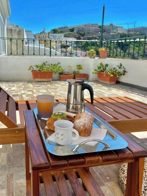 Bandeja com comida e bebida sobre uma mesa de madeira, com vista para a paisagem urbana.