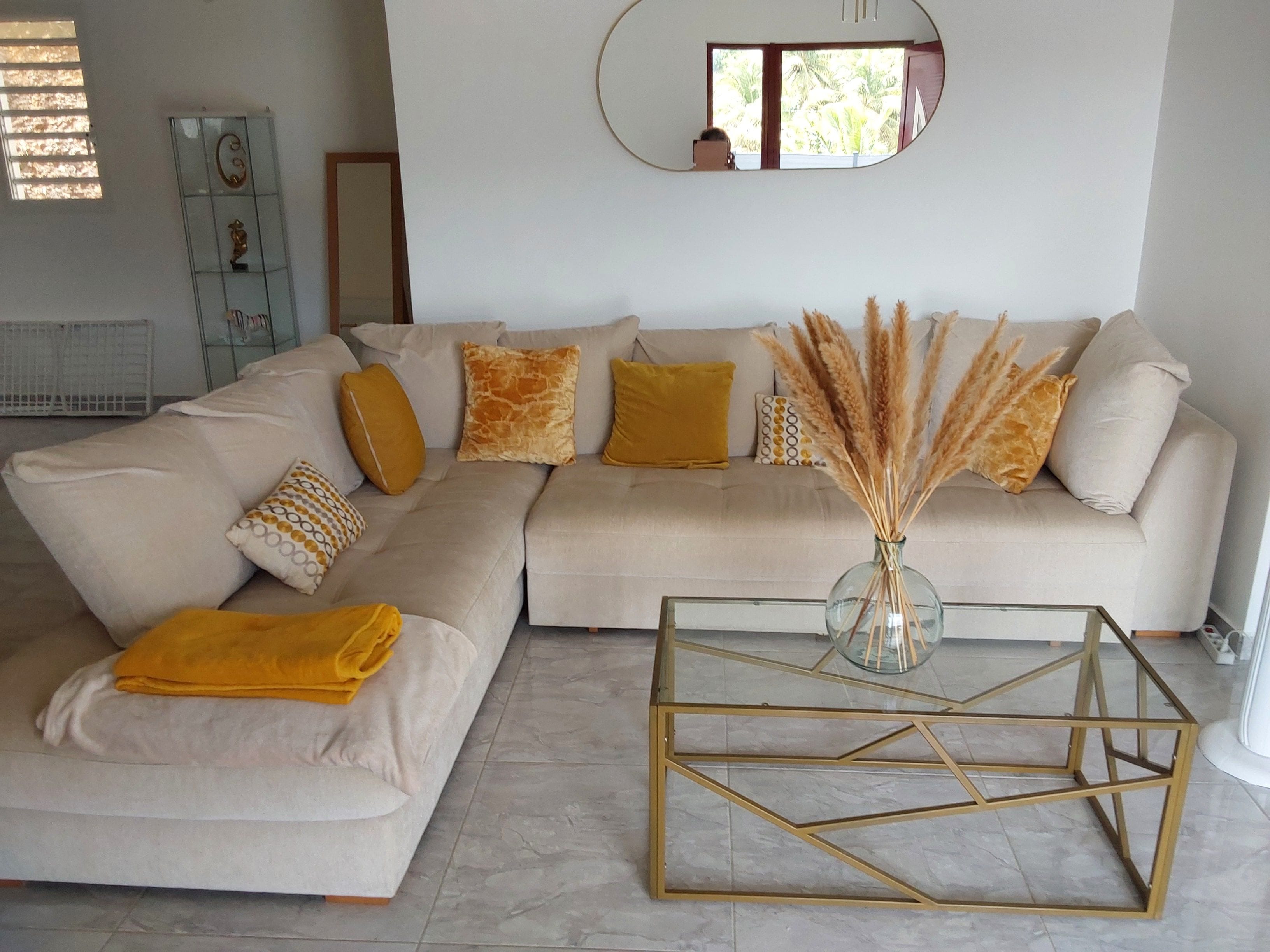 A modern living room with a sectional sofa, a glass coffee table, and a decorative vase.