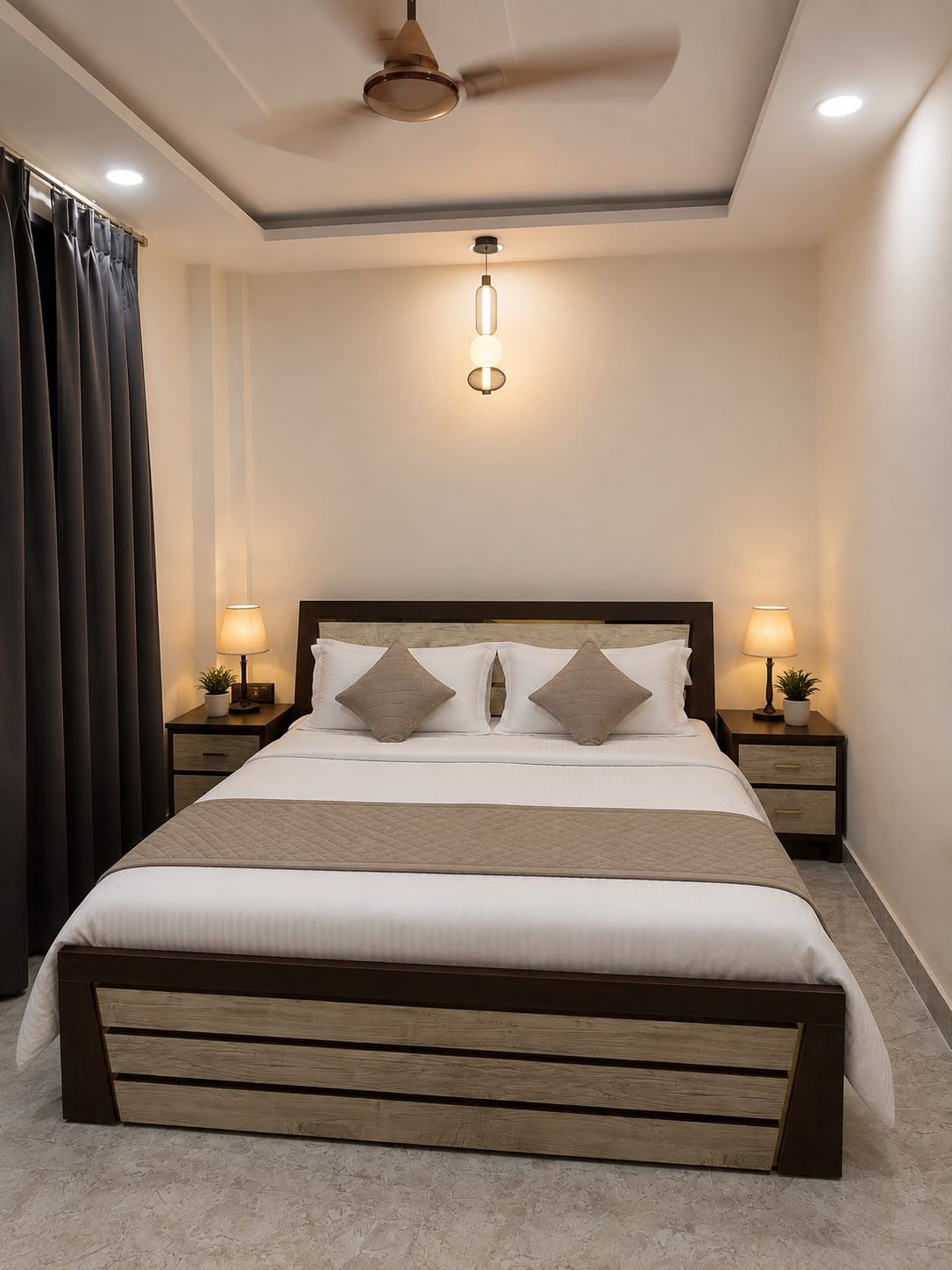 A bedroom with a bed, two bedside tables with lamps, a ceiling fan, and a window with curtains.