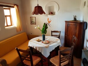 Un comedor con una mesa redonda, sillas, un sofá, un armario y una ventana con cortinas.