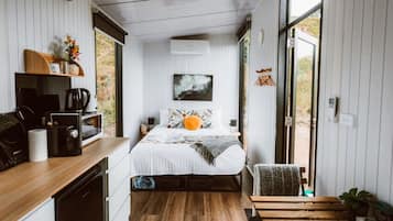 A compact bedroom with a bed, bedside table, and a view through a sliding door.