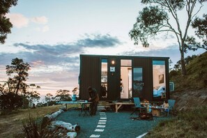 Une cabane moderne dotée d’une terrasse, d’un espace salon extérieur et offrant une vue sur le paysage environnant.