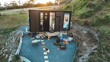 A modern cabin with a patio area, outdoor seating, and a fire pit.