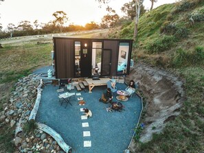 Une cabane moderne dotée d’un patio, d’un espace salon extérieur et d’un foyer.