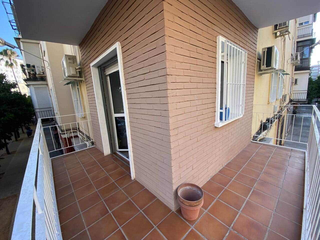 A balcony with a tiled floor, a door, and a window with white bars.