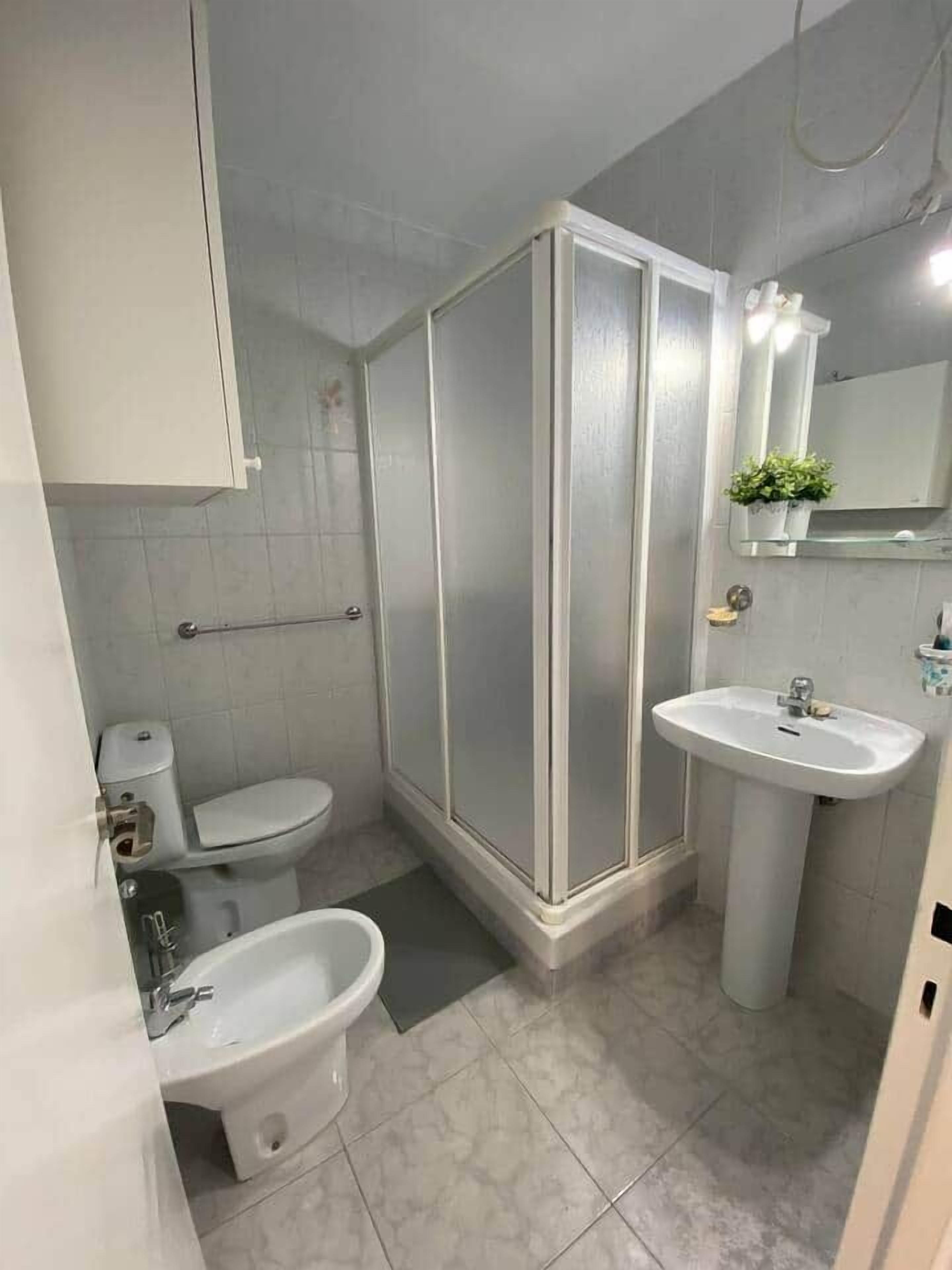 Ein Badezimmer mit Toilette, Bidet, Waschbecken und einer Duschkabine.