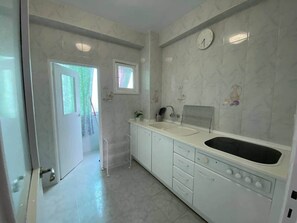 A kitchen with white cabinets, a sink, and a stove. - Nalón Apartments Seville (Seville)