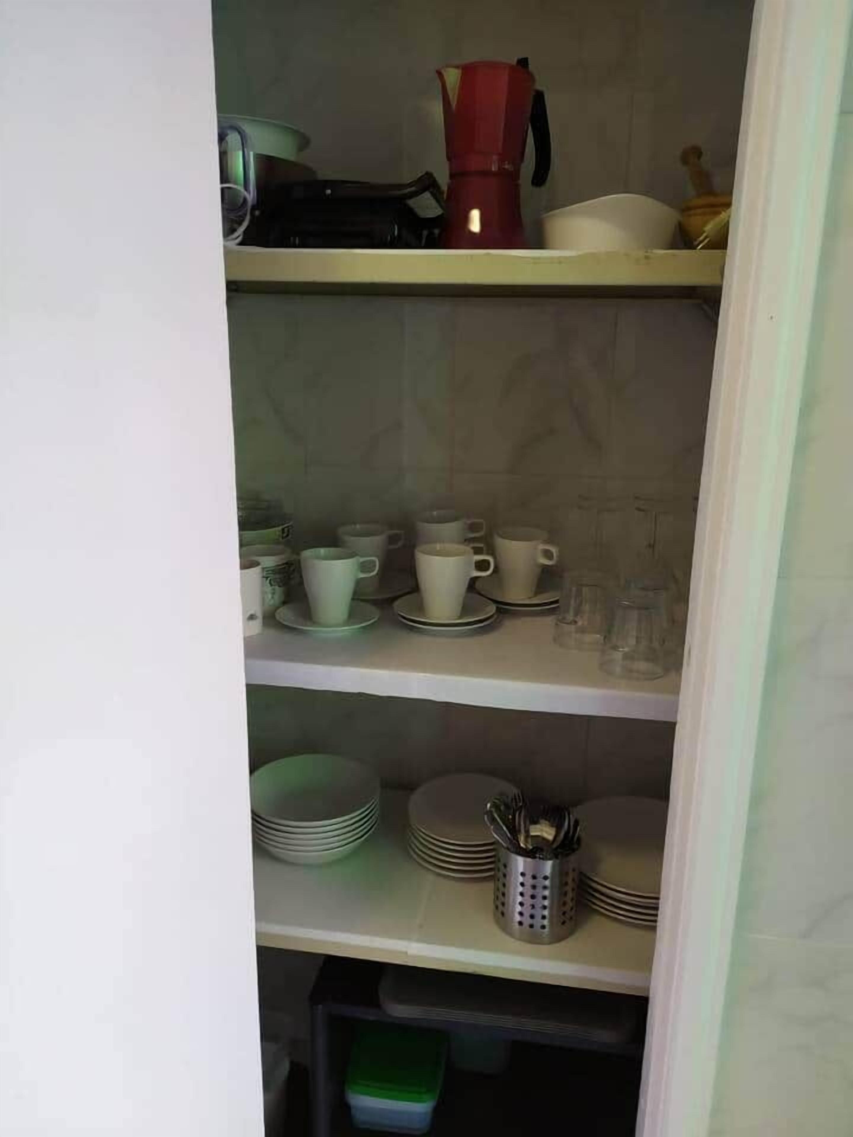 A kitchen with shelves holding various dishes, cups, and a coffee maker.