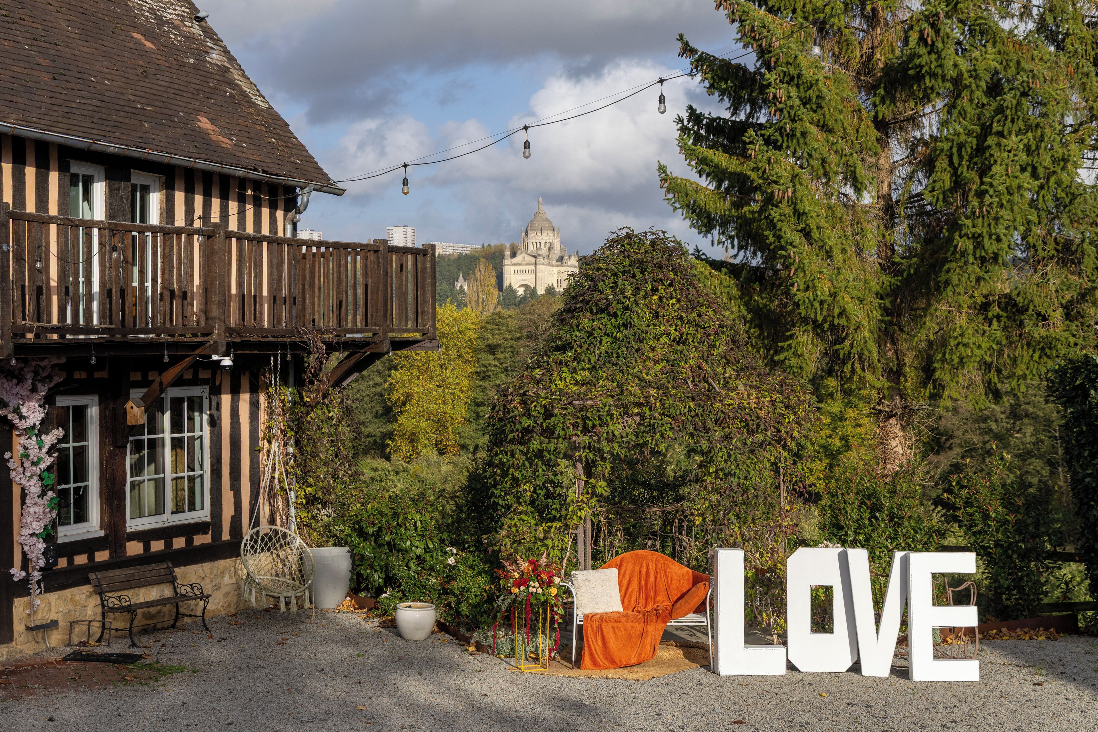 Ein traditionelles Gebäude mit einem Balkon, einem großen Schriftzug 'LOVE' und einer in der Ferne sichtbaren Kathedrale.