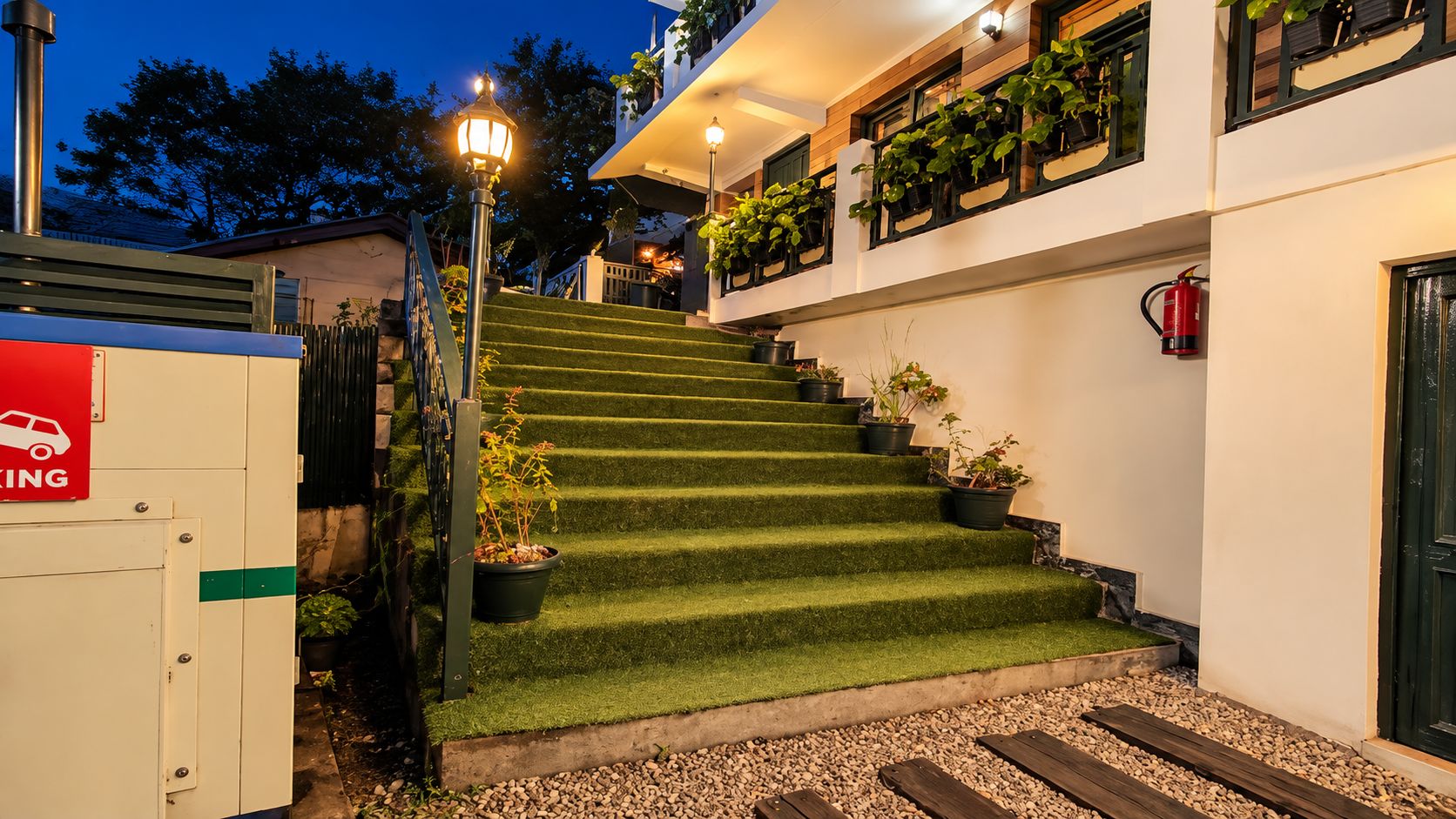 A staircase with artificial grass steps leading to a building with a fire extinguisher mounted on the wall.