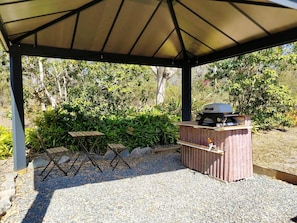 Una terrazza esterna con una griglia, sedie pieghevoli e un tavolo.