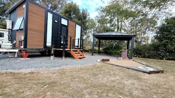 A modern, compact house with a covered outdoor area and a gravel driveway.