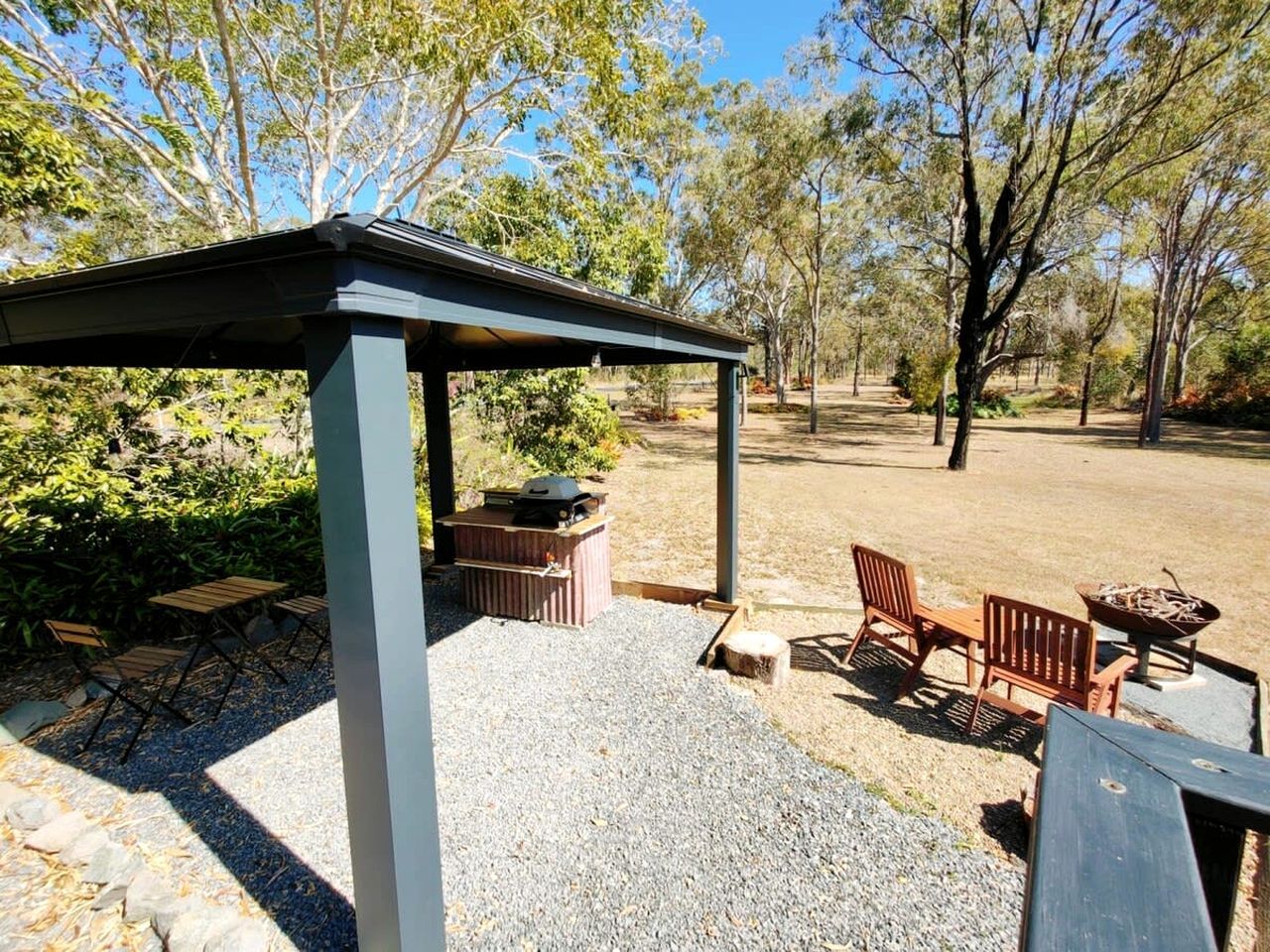 Un espace extérieur aménagé avec un coin salon, une structure couverte, un barbecue et un foyer.