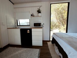 Ein gemütliches Schlafzimmer mit einer Küchenzeile, einem Bett und Blick durch eine Schiebetür.