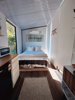 Una camera da letto con un letto, un comodino, un forno a microonde e una finestra.