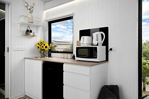Une cuisine compacte équipée d’un four à micro-ondes encastré, d’une machine à café et d’une fenêtre donnant sur l’extérieur.