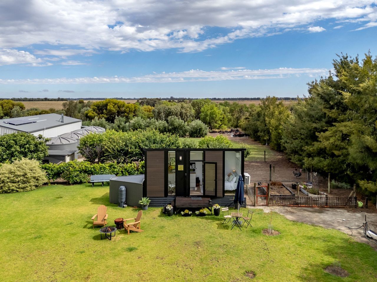 Een modern, compact vakantiehuisje met een terras, omgeven door een weelderige tuin en vrij uitzicht op het landschap.