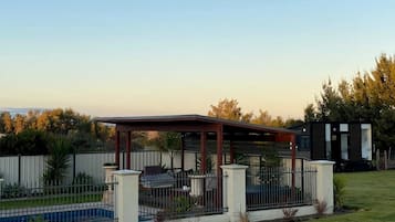 A covered outdoor area with a pool, surrounded by a fence and a small building.
