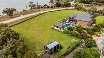 A residential property with a large lawn, a swimming pool, and a detached garage.