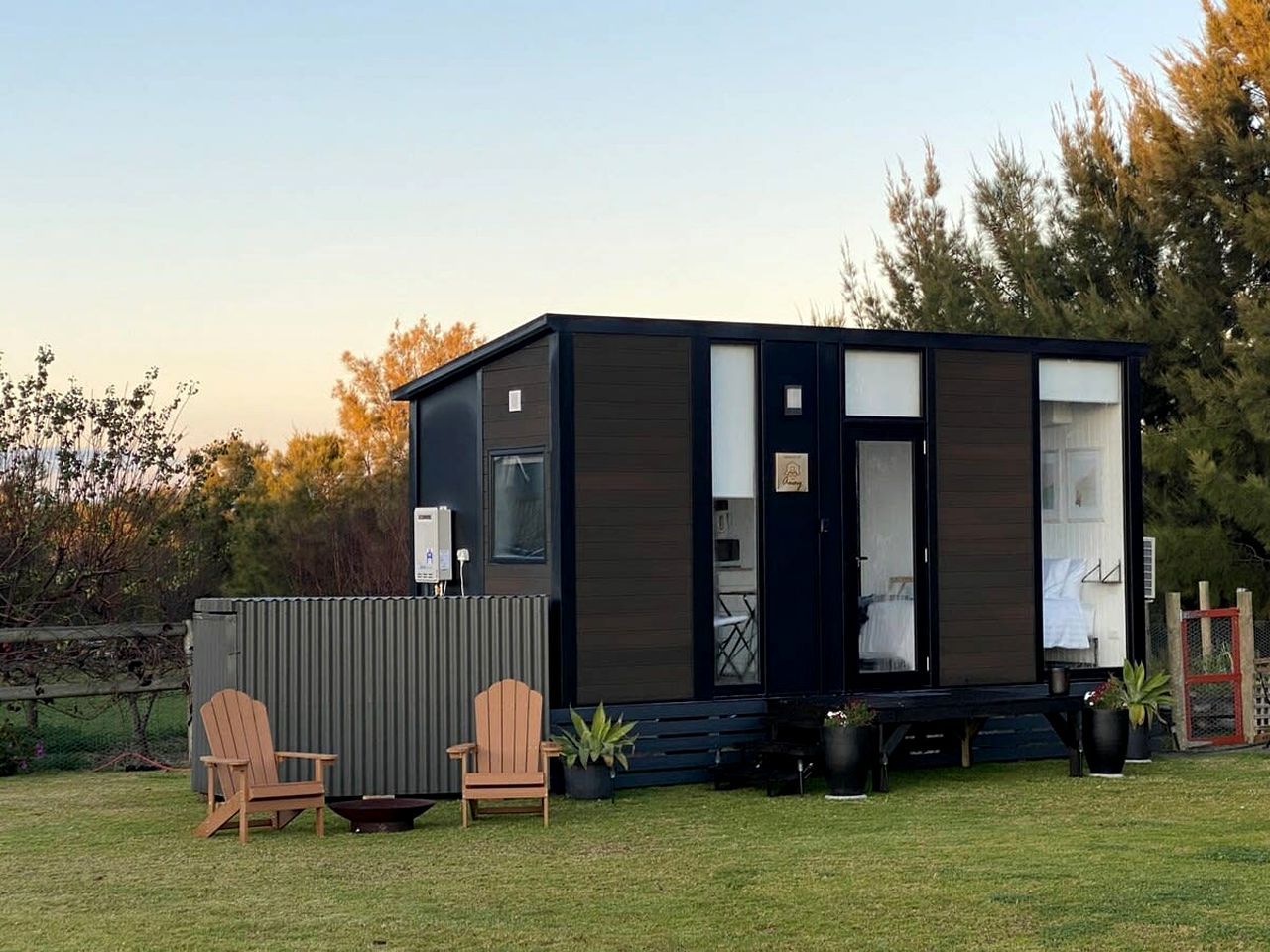 A modern mobile home with a deck, two chairs, and a small table.