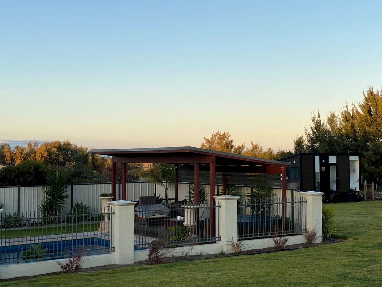 A covered outdoor area with a pool, surrounded by a fence and a small building.
