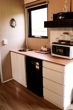 Una cucina compatta con forno a microonde, lavello e lavastoviglie.