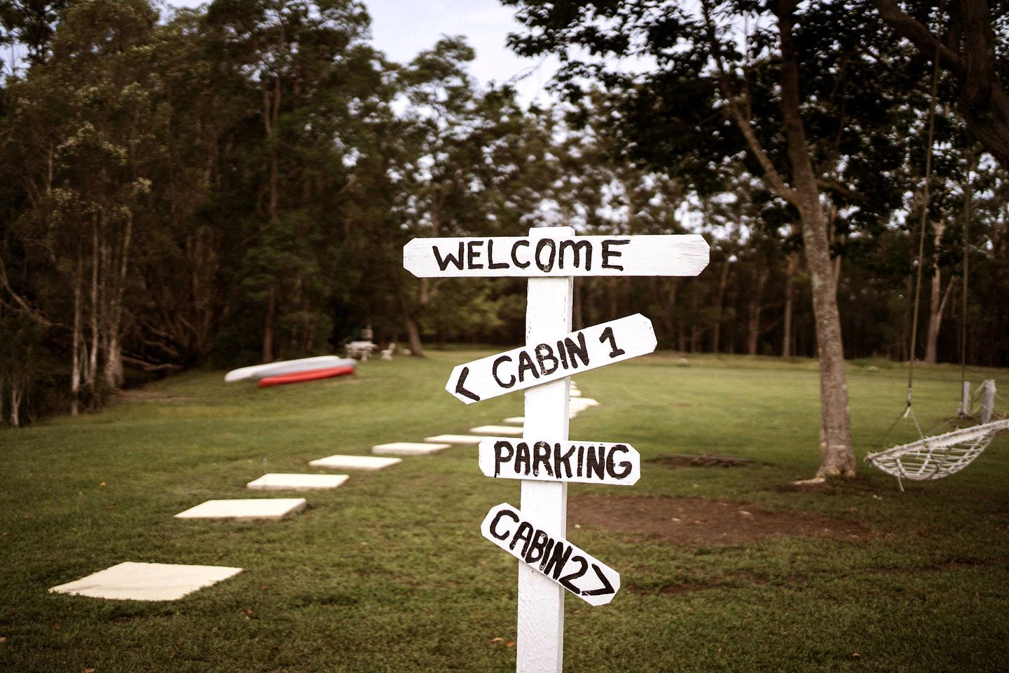 A directional signpost with arrows pointing to 'Welcome', 'Cabin 1', 'Parking', and 'Cabin 2'.