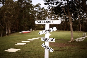 A directional signpost with arrows pointing to 'Welcome', 'Cabin 1', 'Parking', and 'Cabin 2'. - Cozy Tiny House Surrounded by Trees in Coffs Harbour, New South Wales (Coffs Harbour)