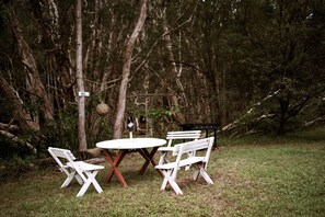 Un'area pranzo all'aperto con un tavolo rotondo e quattro sedie, immersa tra gli alberi.