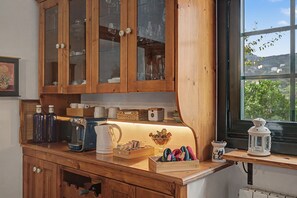 Eine Küche mit Holzausstattung, einer Kaffeemaschine und einem Fenster mit Blick auf Grünflächen.