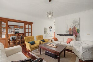 Ein Wohnzimmer mit Essbereich, einer Sofagarnitur, einem Couchtisch und einem Gemälde eines historischen Gebäudes.