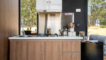 A compact kitchen with wooden cabinets, a gas stove, and a view of the outdoors.