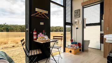 Una habitación con un ventanal grande, una mesa con objetos, un banco y vistas al exterior.