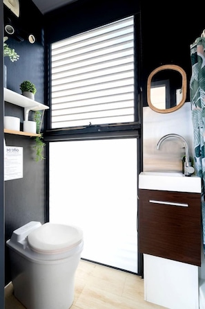 A compact bathroom with a toilet, sink, and window blinds.