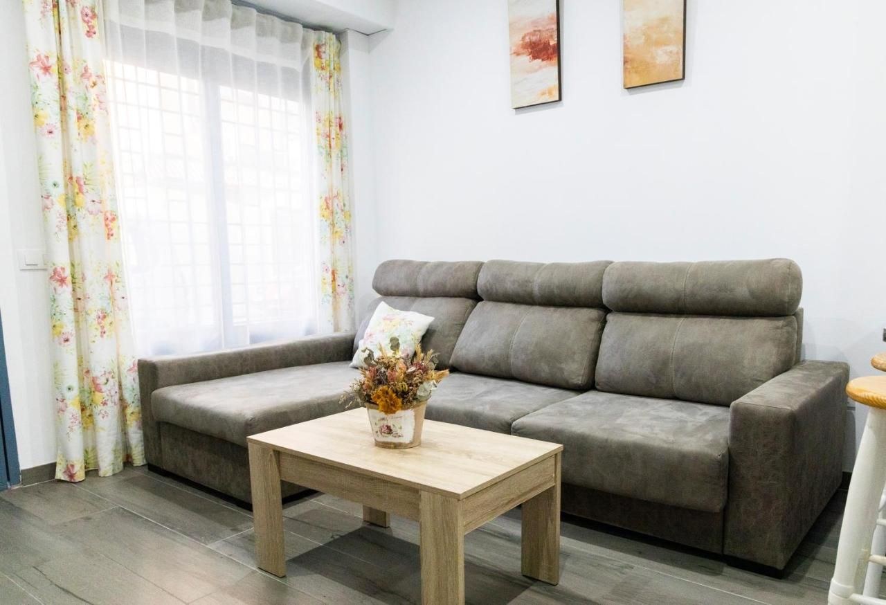 Una sala de estar con un sofá gris, una mesa de centro de madera y una cortina estampada.