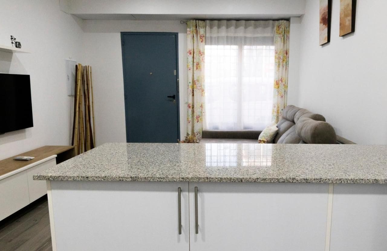 Una cocina moderna con encimera de granito, armarios blancos y una puerta azul.