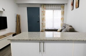 Una cocina moderna con encimera de granito, armarios blancos y una puerta azul.