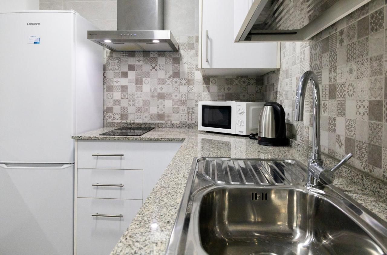 Una cocina con un lavaplatos de acero inoxidable, un microondas y un refrigerador.