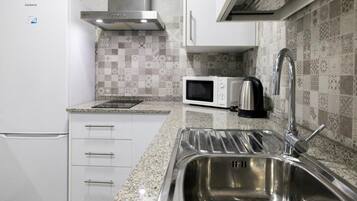 Una cocina con un lavaplatos de acero inoxidable, un microondas y un refrigerador.