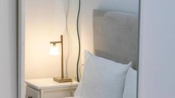 Un dormitorio con cama, mesita de noche, lámpara y espejo.