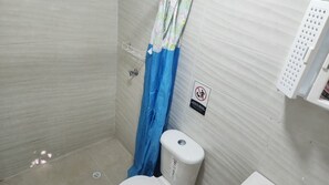 Un baño pequeño con inodoro, cortina de ducha y un cartel de prohibido fumar.
