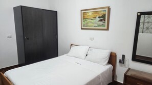 Une chambre à coucher avec un lit, une armoire, un tableau, un miroir et une table de chevet.